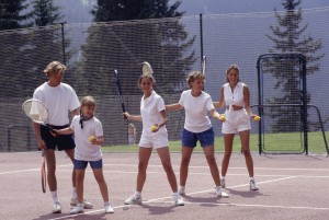 Group of people practising tennis with coach