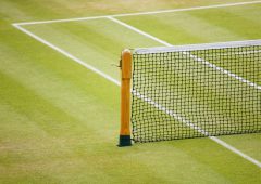 Detail of a tennis net and post on a grass court
