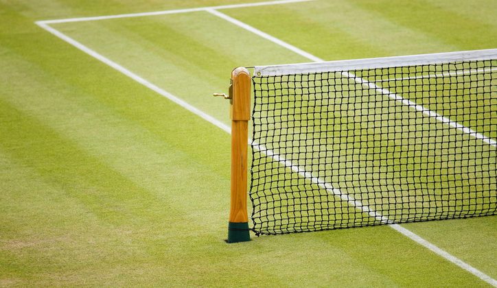 Detail of a tennis net and post on a grass court